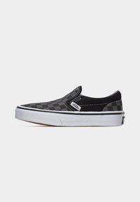 Μαύρο και γκρι παπούτσι Vans slip-on με σχέδιο σκακιέρας, λευκή σόλα και μαύρη ρίγα, φωτογραφημένο από το πλάι σε λευκό φόντο.