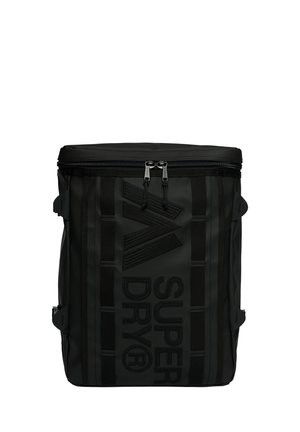 Zwarte rechthoekige rugzak met bovenste rits, twee ritsen, verticale strepen en groot gestructureerd "Super Dry" logo aan de voorkant.
