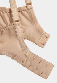 Beige bh med mesh-stof, justerbare stropper og lukning med hægte og øje. Har bløde blonder langs kanterne.