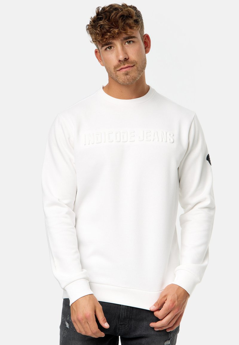Witte sweatshirt van zacht materiaal, met een gestructureerd logo "INDICODE JEANS" op de borst en ribbelmanchetten en onderrand.