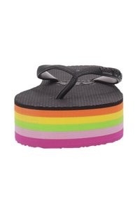 Chancla negra con una suela gruesa de colores en capas, que muestra franjas horizontales de color naranja, verde, rosa y morado, y una plantilla texturizada.