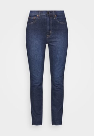 Mørkeblå denim jeans med slim fit, fem lommer, lynlås, sømdetaljer og kobberhardware accenter. Glat tekstur med minimal falming.