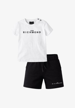 T-shirt bianca a maniche corte con scritta "John Richmond" e bottoni neri sulla spalla, abbinata a pantaloncini con vita elastica neri con scritta del logo.