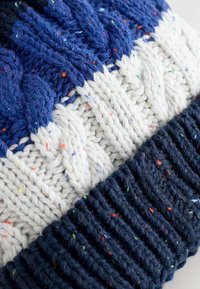 Gebreid sweater met een gestructureerd ontwerp met donkerblauw, crème en gespikkeld garen. Kabelbrei- en ribbelsecties creëren contrast.