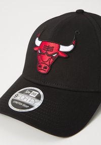 Gorra negra con un logo bordado en rojo y blanco de los Chicago Bulls, que presenta una corona redondeada, visera curvada y un ajuste trasero de tipo stretch-snap.