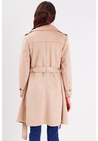 Beige trench coat with a belted waist, long sleeves, and a tailored fit. Textured material with a smooth finish, featuring a classic collar.