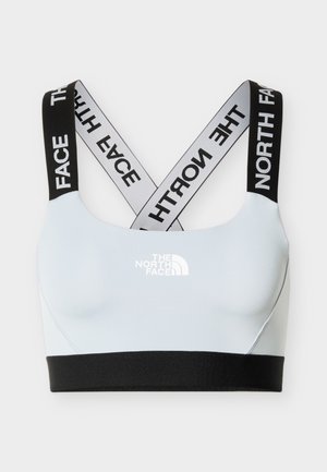 Light blue sports bra with black elastic band and crossed black-and-white straps featuring "THE NORTH FACE" logo.