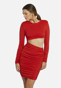 Rotes langärmeliges Kleid mit einem kurzen Oberteil und seitlichem Ausschnitt, das gerafften Stoff für einen strukturierten Look aufweist. Figurbetonte Silhouette.