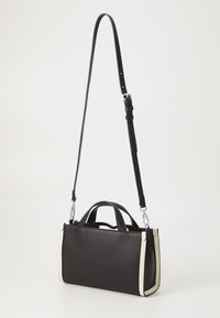 Borsa nera con texture, dotata di doppi manici e tracolla removibile, con accenti crema sui bordi e accessori in argento.