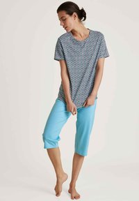 Patroon chemise met korte mouwen in blauw, groen en wit met een ronde halslijn, gecombineerd met lichtblauwe capri-broeken, zacht materiaal, losse pasvorm.