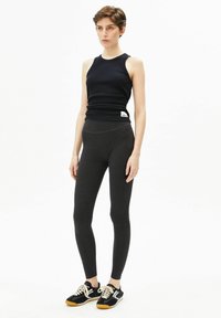 Zwart geribd tanktop gecombineerd met donkergrijze legging. De tanktop is aansluitend met een ronde hals, terwijl de legging een hoge tailleband en een gladde textuur heeft.