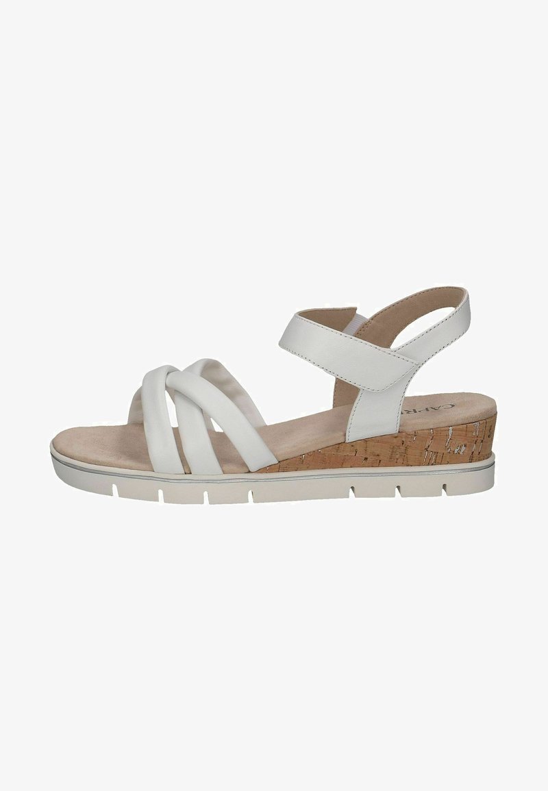 White sandal with crossover straps, cork-like wedge heel, textured base, and adjustable ankle strap. Soft footbed with a neutral finish.