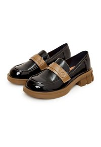 Mocassins en cuir verni noir avec semelles épaisses en caoutchouc marron et brides assorties marron à l'avant, ornées d'un petit logo circulaire.