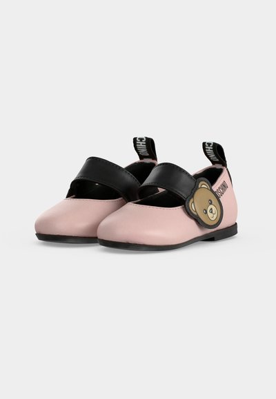 Paire de chaussons bébé roses avec des sangles noires, détail visage d'ours sur le côté, et languettes noires avec marquage blanc à l'arrière.