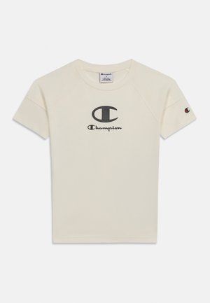 T-shirt Champion couleur crème à manches courtes, col rond, grand logo noir et texte centrés sur la poitrine, et petit logo sur la manche gauche.