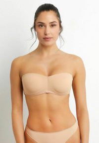 Strapless nude bra with smooth fabric, molded cups, and minimalist design. Features seamless edges and a subtle sheen.