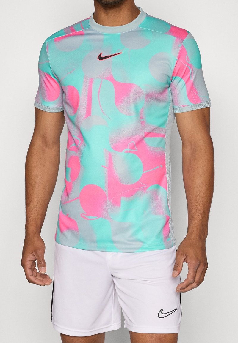 Nike kortärmad träningsskjorta med en ljusblå bas och abstrakta mönster i rosa och grått. Tillverkad av ett slätt, elastiskt material för komfort.