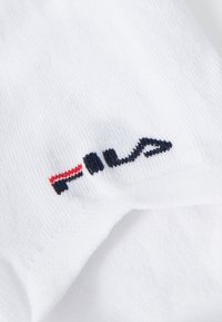 Biely bavlnený materiál s vyšitým logom Fila v námorníckej modrej a červenej farbe. Dizajn obsahuje čisté línie a jemnú textúru.