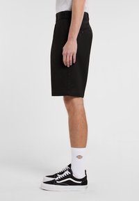 Black shorts made of a lightweight fabric, featuring a straight cut, front and back pockets, and a belt loop waistband.