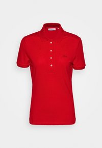Rød bomulds polo shirt med krave, tre-knaps knaplukning og et lille broderet logo på venstre bryst. Korte ærmer og ensfarvet.