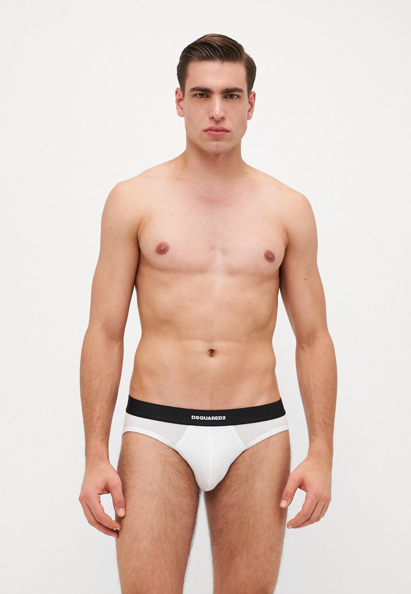 Culottes blanches avec une ceinture élastique noire portant le logo "DSQUARED2". Tissu lisse, design ajusté et style classique pour un confort optimal.