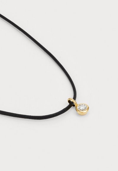 Collana in pelle nera con pendant dorato che presenta una pietra preziosa trasparente di forma circolare. Design semplice con dettagli minimi e una texture liscia.