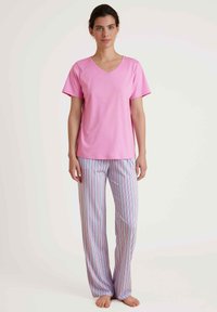 Roze V-hals t-shirt met korte mouwen, gecombineerd met gestreepte slaapbroeken in pastelkleuren, met rechte pijpen en een relaxte pasvorm.