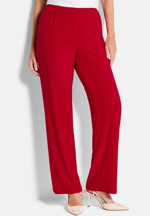 Vrouw draagt felrode wijde broek met elastische tailleband en beige slingback pumps met hoge hak.