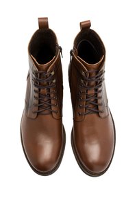 Brązowe skórzane buty za kostkę o gładkiej fakturze, wiązane, z kontrastującymi ciemnobrązowymi sznurowadłami. Posiadają krótki uchwyt z tyłu.