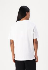 Λευκό βαμβακερό μπλουζάκι με κοντά μανίκια, στρογγυλή λαιμόκοψη και άνετη εφαρμογή. Λείο υλικό, απλή σχεδίαση, χωρίς ορατά μοτίβα ή διακοσμητικά στοιχεία.