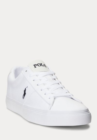 Biały niski sneaker z sznurowadłami, czarne logo Polo po boku oraz tekst "POLO" na języku, pokazany pod lekkim kątem na jednolitym tle.