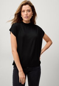 Sort kortærmet top med høj hals og afslappet pasform. Lavet af glat, let stof med et minimalistisk design.