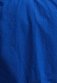 Μοναδικό μπλε ύφασμα με ορατές τσακίσεις και πτυχές, που δείχνει υφή και ελαφριές σκιές.