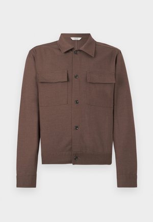 Καφέ σακάκι με μακριά μανίκια, μυτερό γιακά, κλείσιμο με κουμπιά μπροστά και δύο τσέπες στο στήθος με καπάκι, σε απλό φόντο.