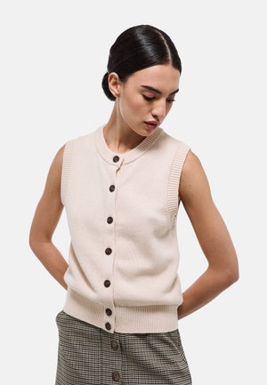 Cardigan sans manches beige avec des bords côtelés et un col rond, présentant des boutons marron sur le devant et une texture douce.