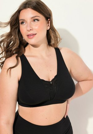 Zwarte bralette met een diepe V-hals, met kantdetails en een knoopaccent. Gemaakt van zachte stof, ontworpen voor comfort en ondersteuning.