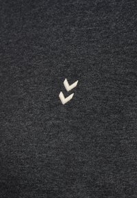 Dark gray T-shirt made of soft, textured fabric; features a small white logo stitched on the left side. Simple, casual design.