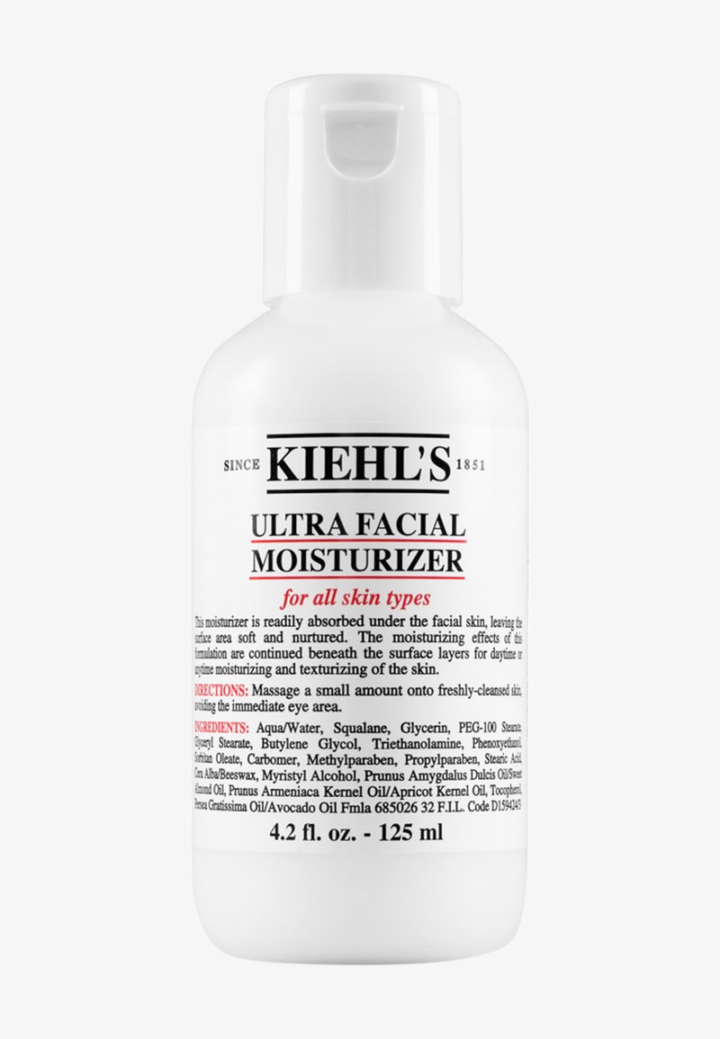 Hvit plastflaske med pumpe-dispenser. Etiketten har svart og rød tekst. Produktet er en ansiktskrem som passer for alle hudtyper.