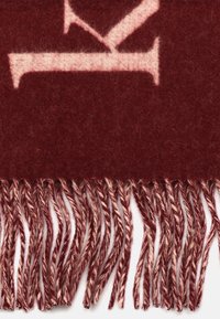 Scialle di lana bordeaux con una texture morbida, caratterizzato da un bordo frangiato con filamenti attorcigliati di una tonalità più chiara di bordeaux.