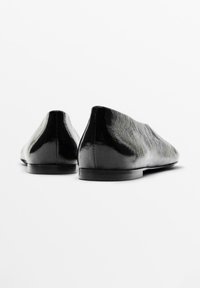Ballerines en cuir noir au fini lisse, à bout pointu, au design minimaliste et à la silhouette subtile, présentant une semelle basse et flexible.