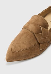 Καφέ μοκασίνια από σουέντ με μυτερή μύτη, διακοσμημένα με φαρδιά λωρίδα και διακριτικές ραφές κατά μήκος των άκρων, καθώς και με λεία εσωτερική επένδυση.