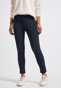 Marina stretchleggings tillverkade av ett mjukt tyg, med hög midja och avsmalnande ankelöppningar, matchade med vita sneakers.