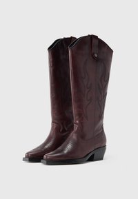 Μπορντό δερμάτινες καουμπόικες μπότες με κεντήματα φλόγας, υφή στη μύτη, στρωμένο τακούνι και θηλιές στο πάνω μέρος για εύκολη φορεσιά.