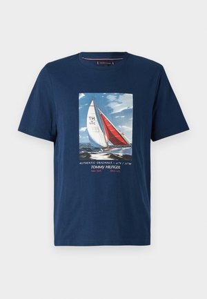 T-shirt in cotone blu con grafica di una barca a vela con vele rosse e bianche, e il testo "Tommy Hilfiger" e "Authentic Originals" in basso.