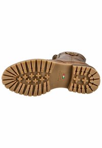 Semelle de botte en cuir marron avec un motif de gomme profond, comportant des formes de croix et d'étoiles. L'étiquette indique "Fabriqué en Italie".