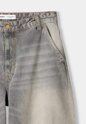 Light grey denim jeans with a faded pattern, featuring orange stitching, a button closure, and side pockets.