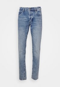 Jean denim bleu coupe slim avec fermeture à bouton et zip devant, deux poches avant et deux poches arrière, présenté sur un fond blanc uni.