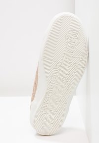 Zapatilla de color rosa claro con parte superior texturizada, suela de goma blanca con un diseño de dibujo y logo de la marca en relieve en la suela.