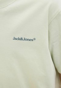 Világoszöld pamut póló, kerek nyakkivágással, bal mellkas területén sötétkék "Jack & Jones" logóval. Puha tapintású.