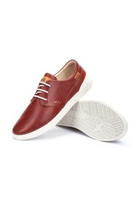Zapatos de cuero rojo con parte superior perforada, suela de goma blanca y acentos decorativos en color marrón claro. Presenta un diseño de cordones y una suela texturizada.